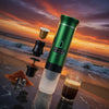Green portable coffee maker with a glass of coffee on a beach at sunset